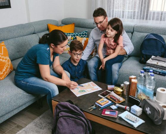 Family gathered around living room coffee table with emergency supplies planning for emergency.