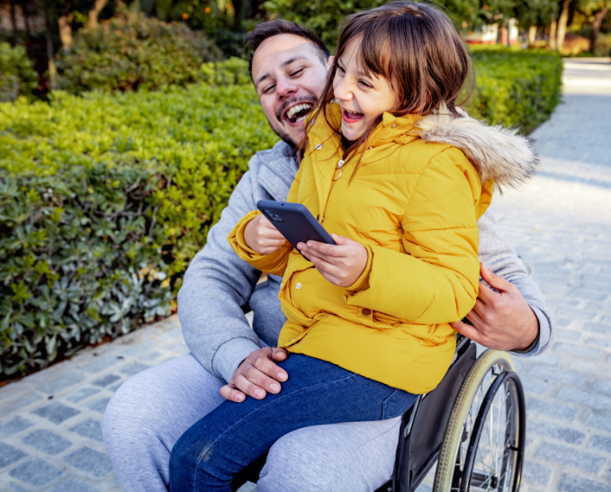 Man in wheelchair with daughter sitting in lap.
